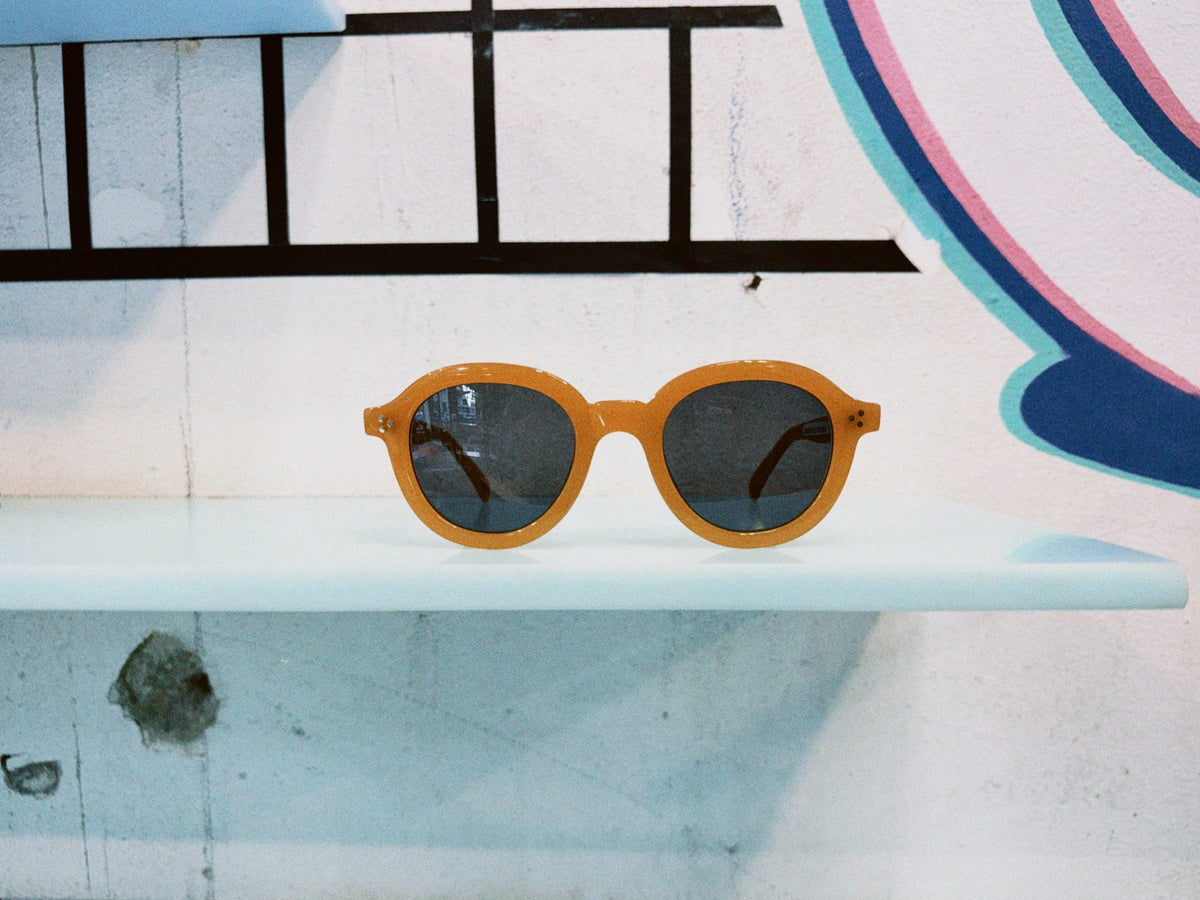 Vincent Kaes Sonnenbrille mit orangefarbener runder Fassung und dunklen Gläsern